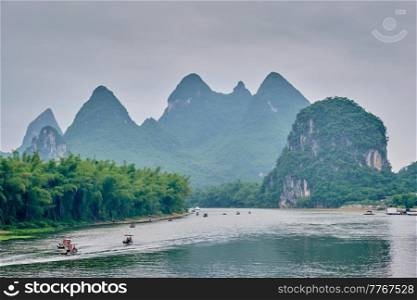 Tourist boats on Li river with dramatic karst mountain landscape in the background. Yangshuo, China. Tourist boats on Li river with carst mountains in the background