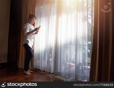 Tourist Chinese woman standing at room door hand using phone at hotel while having leisure time in vacation.