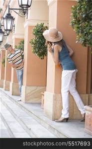 Tourist couple looking at each other while hiding behind columns