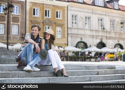 Tourist couple sitting on steps against building