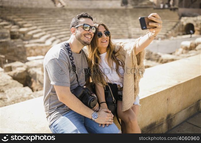 tourist couple sitting together taking selfie through cell phone
