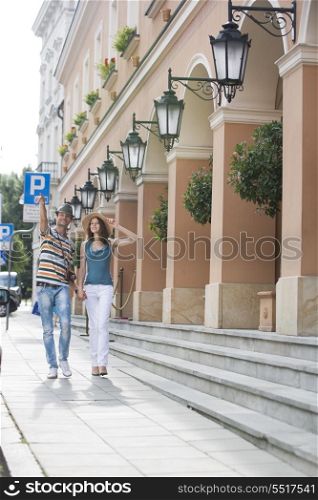 Tourist couple walking on sidewalk along building