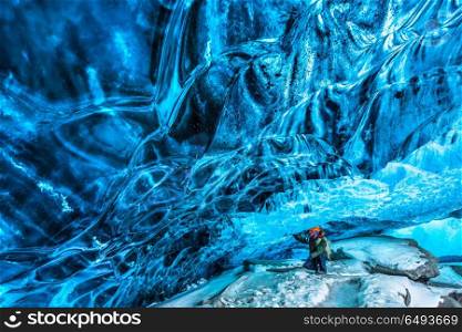 Tourist discovering the ice cave, active traveler man enjoying beauty of a glacial cave, extreme winter vacation, Skaftafell national park, Vatnajokull, Iceland. Traveler in the ice cave