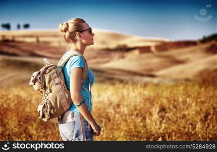 Tourist girl enjoying view of beautiful dry golden wheat hills, traveling along Europe in autumnal season, active lifestyle concept