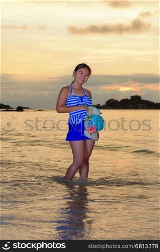 Tourist girl in a blue striped swimsuit pose with happiness on the beach and beautiful landscape of sky over the sea during sunrise at Koh Miang Islands, Mu Ko Similan National Park, Phang Nga, Thailand