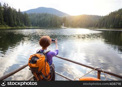 tourist girl making a photo shoot of mountain lake synevyr. Carpathians, Ukraine.