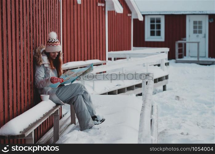 tourist girl sits near rorbu with a map at the lofoten islands. Norway