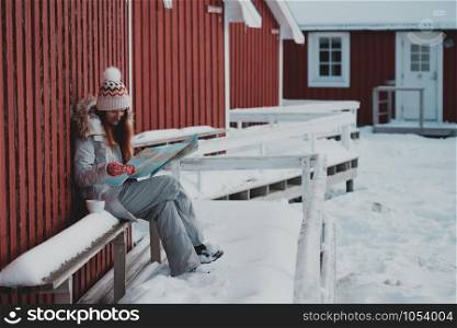 tourist girl sits near rorbu with a map at the lofoten islands. Norway