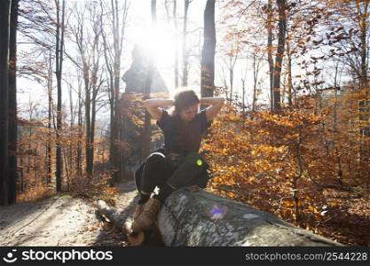 tourist girl sitting on a log in the autumn forest. Carpathians mountains.
