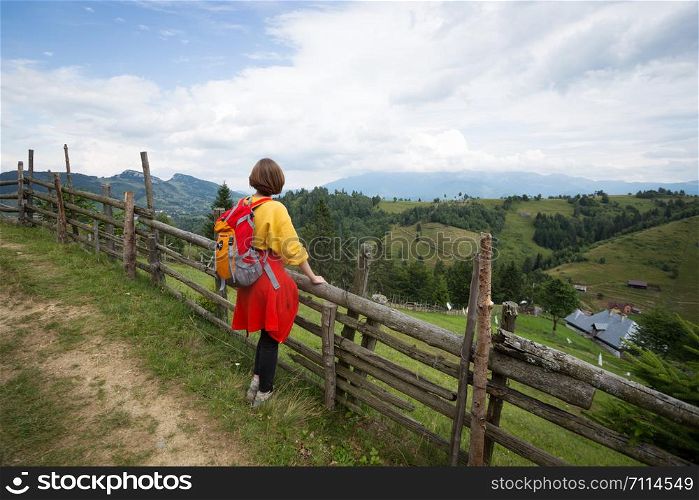 tourist girl standing at the mountains and looks at the valley