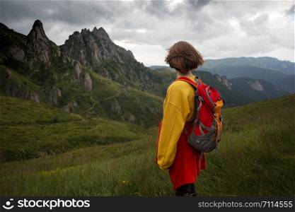 tourist girl standing on the trail and Ciucas Mountains in the background. Romania