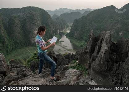 Tourist girl Standing view map of the peak on the mountain. at Hang Mua, Ninh Binh in Vietnam.