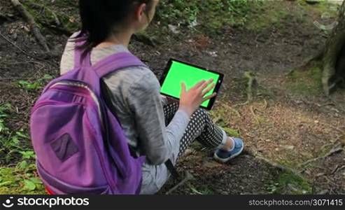 Tourist girl using a tablet pc with copy space in the forest.