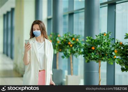 Tourist girl wearing a mask for prevent virus with baggage in international airport. Protection against Coronavirus and gripp. Young tourist woman with baggage in international airport