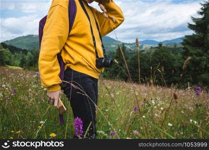 tourist girl with a backpack and camera standing in the meadow at the mountains. Carpathians. Ukraine