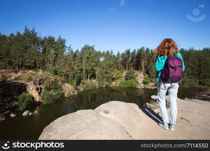 tourist girl with a backpack standing on the shore the lake