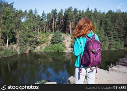 tourist girl with a backpack standing on the shore the lake