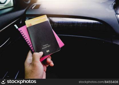 Tourist hand holding passport, credit card, notepad in a hand on the car,copy space