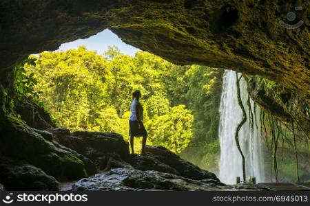 Tourist In cave looking out at Misol Ha Waterfall near Palenque in Chiapas, Mexico