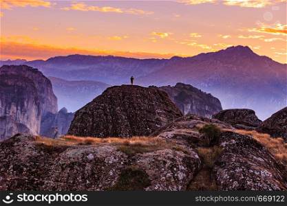 Tourist in mountains at sunset, person on cliffs rocky formations in Thessaly Greece. Tourism vacation and travel. Tourist in mountains Meteora Greece