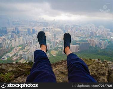Tourist legs with Hong Kong Downtown, republic of china. View from mountain in travel trip and holidays vacation concept. Smart urban city in Asia. Skyscrapers and high-rise modern buildings.