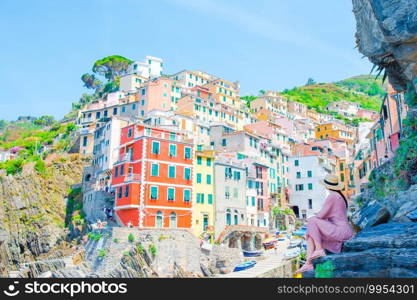Tourist looking at scenic view of Riomaggiore, Cinque Terre, Liguria, Italy. Young woman with great view at old village Riomaggiore, Cinque Terre, Liguria, Italy. European italian vacation.