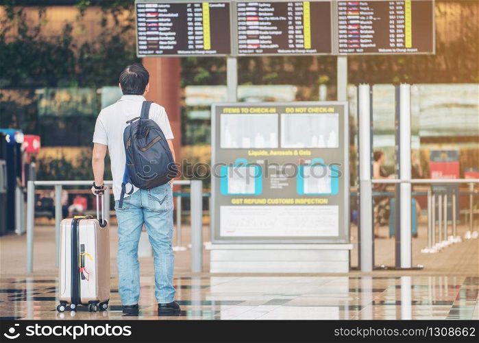 Tourist man looking at flight information board in international airport terminal