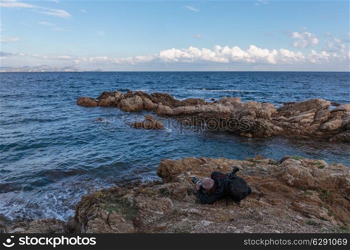 Tourist on a cliff photographing the sea, Cote d&rsquo;Azur, France