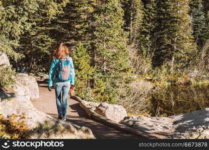 Tourist on trail near Bear Lake in Colorado. Woman tourist walking on trail near Bear Lake at autumn in Rocky Mountain National Park. Colorado, USA.