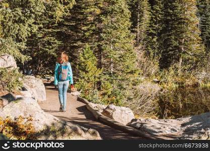 Tourist on trail near Bear Lake in Colorado. Woman tourist walking on trail near Bear Lake at autumn in Rocky Mountain National Park. Colorado, USA.