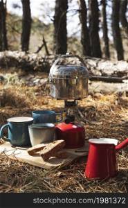 tourist picnic in the forest. burner with cauldron, cups and biscotti. camping aesthetics
