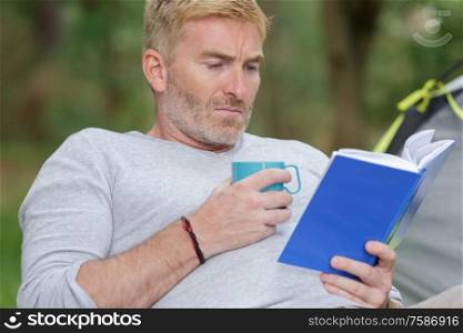 tourist reading a book and drinking tea in a forest
