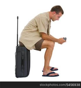 Tourist sitting on bag and checking vacation photos while waiting airplane
