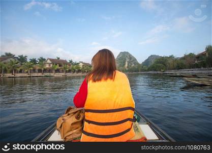 tourist sitting on boat for travel around Tam Coc beatiful nature river and mountain, Tam Coc Ninh Binh, Vietnam. subject is blurred.