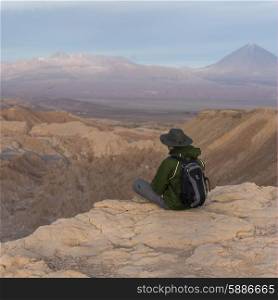 Tourist sitting on edge of cliff, Death Valley, San Pedro de Atacama, El Loa Province, Antofagasta Region, Chile
