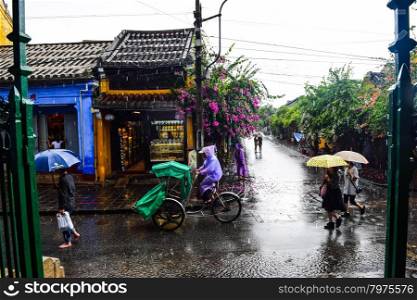Tourist taking a tour to discover Hoi An ancient town by cyclo on a rainy day