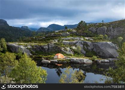 Tourist tent on the shore of a lake in the mountains. Beautiful Nature Norway natural landscape.