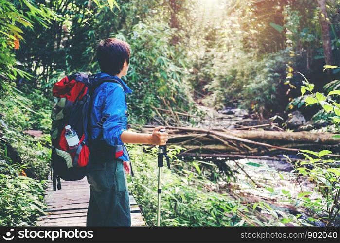 Tourist trail hiking in the forest Traveler Man with backpack crossing the mountain river in forest