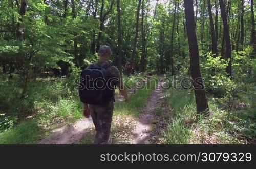 Tourist walking dirt path through a green forest