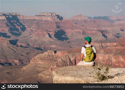 Tourist with backpack at Grand Canyon. Tourist with backpack at Grand Canyon sitting on the rock edge, Arizona, USA