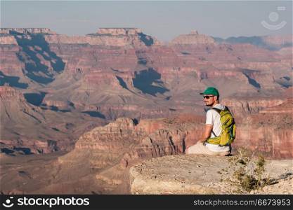 Tourist with backpack at Grand Canyon. Tourist with backpack at Grand Canyon sitting on the rock edge, Arizona, USA