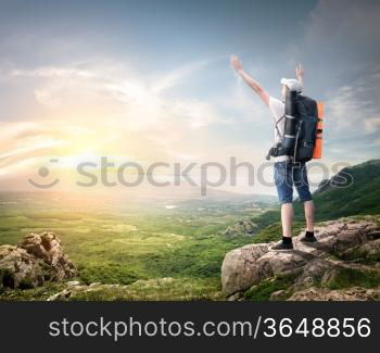 Tourist with backpack enjoy valley view from top of a mountain