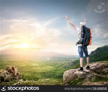 Tourist with backpack enjoy valley view from top of a mountain