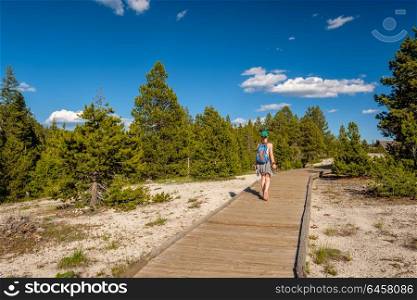 Tourist with backpack hiking in Yellowstone National Park near Firehole River, Wyoming, USA