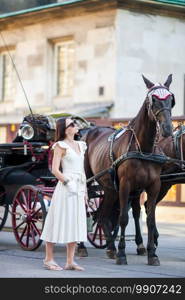 Tourist woman enjoying a stroll through Vienna and looking at the beautiful horses in the carriage. Beautiful girl in Europe. Tourist girl enjoying a stroll through Vienna and looking at the beautiful horses in the carriage