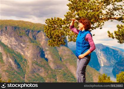 Tourist woman on the mountain top looking at view of fjord mountains, Norway. National tourist scenic route Aurlandsfjellet. Holidays relaxation on trip.. Tourist on mountains top, Norway