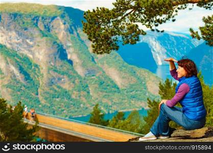 Tourist woman over Stegastein lookout looking at view of fjord mountains, Norway. Hikking, relax on trip. National tourist scenic route Aurlandsfjellet.. Tourist enjoying mountains fjord view, Norway
