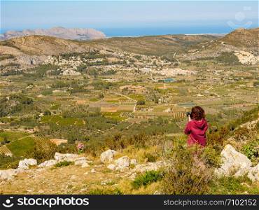 Tourist woman take travel picture from mountains landscape in Spain. Coll de Rates cycling route, view on the way up. Costa Blanca holiday. Woman take photo in mountains