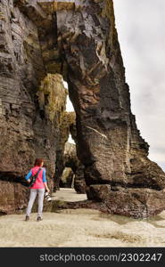 Tourist woman taking travel photo from cliff formations on Cathedral Beach in Galicia Spain. Playa de las Catedrales, As Catedrais in Ribadeo, province of Lugo, northern Spain.. Woman with camera at Cathedral Beach, Galicia Spain.