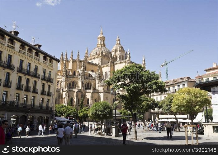Tourists and locals alike enjoying life in Plaza Mayor and the Gothic Cathedral of Segovia, Spain